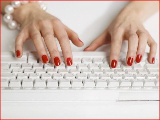 woman with red nail polish typing on computer